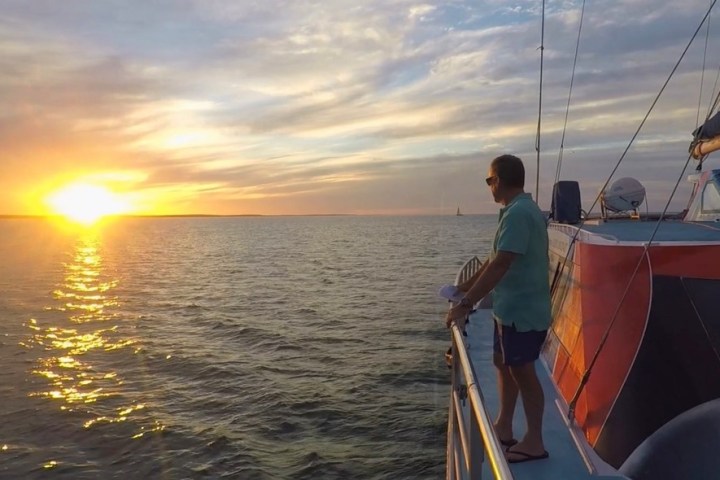 Person on boat watching a bright sunset over the ocean.