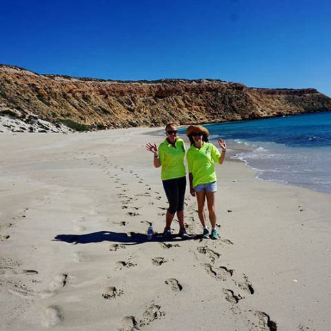 a couple of people that are standing in the sand on a beach