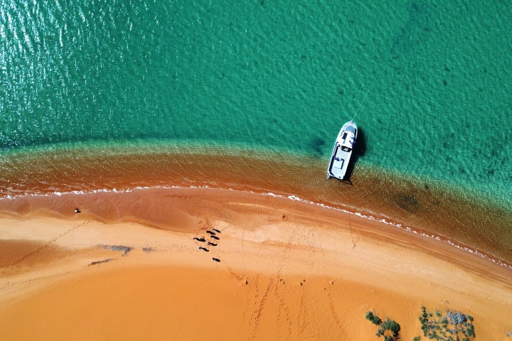 Aerial view of a boat anchored near a sandy beach with turquoise water.