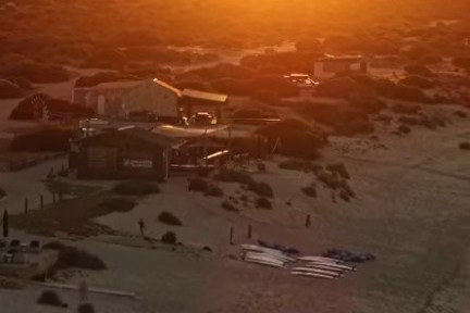 Sunset over a beach with buildings in the distance.